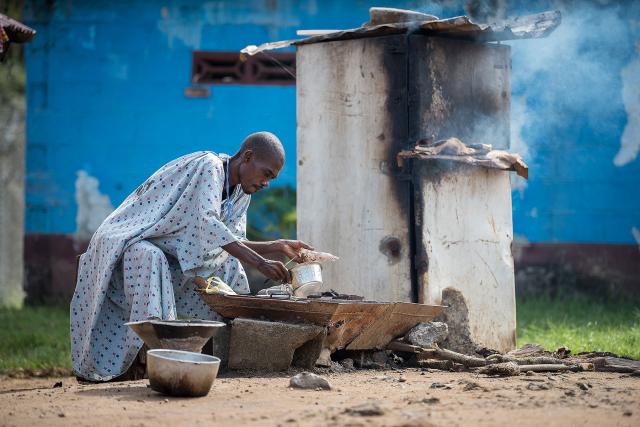 A male patient at the Ganta United Methodist Hospital prepares a meal. The hospital provides kitchen facilities for patients who wish to cook for themselves during their stay.